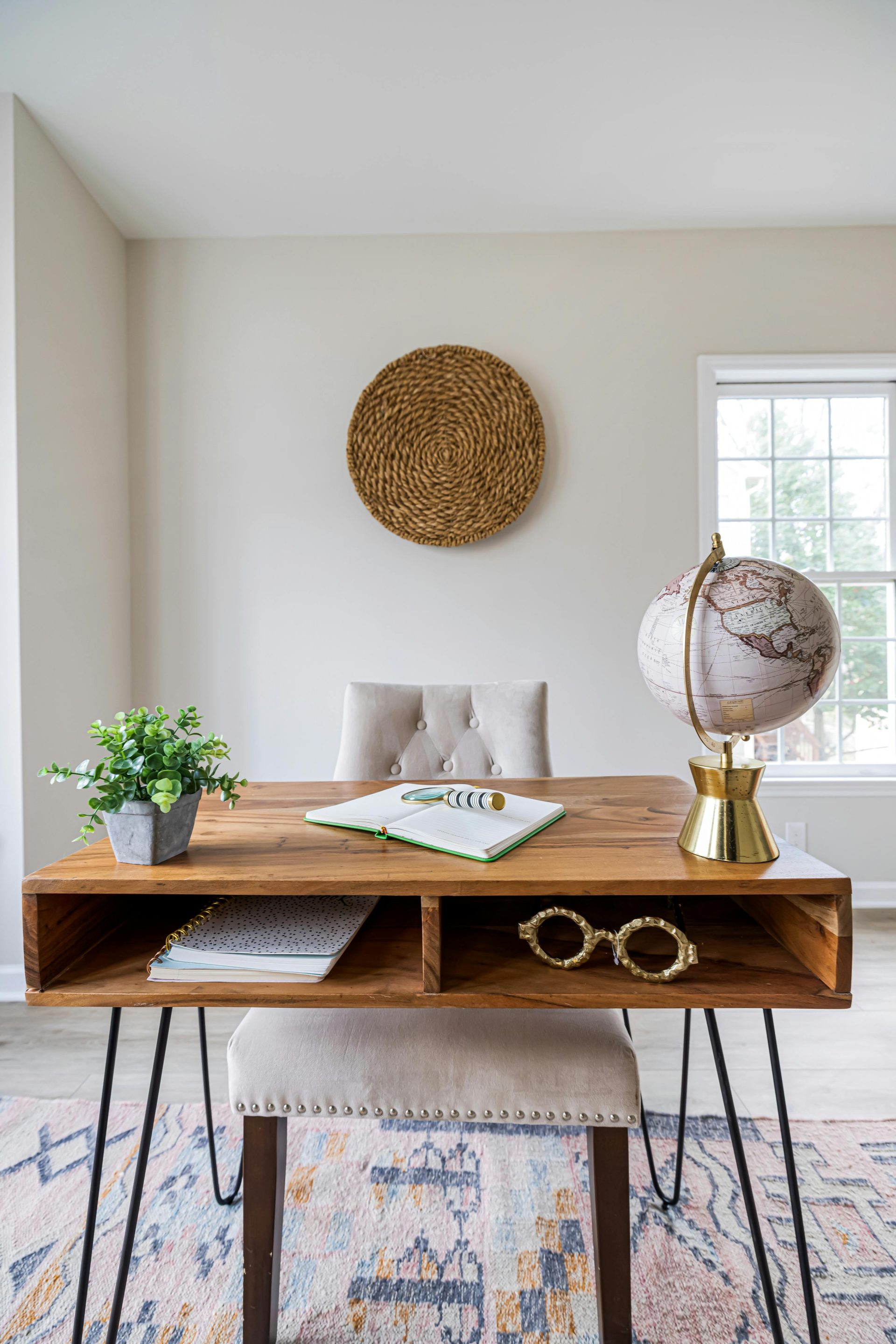 Un bureau à domicile minimaliste comprenant un bureau en bois, une chaise, un globe terrestre et une décoration pour un design intérieur élégant.